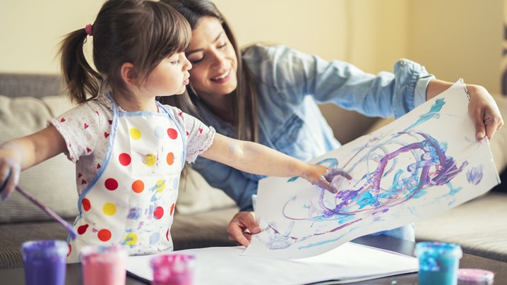 imagem de mãe e filha a pintar com tinta numa folha de papel